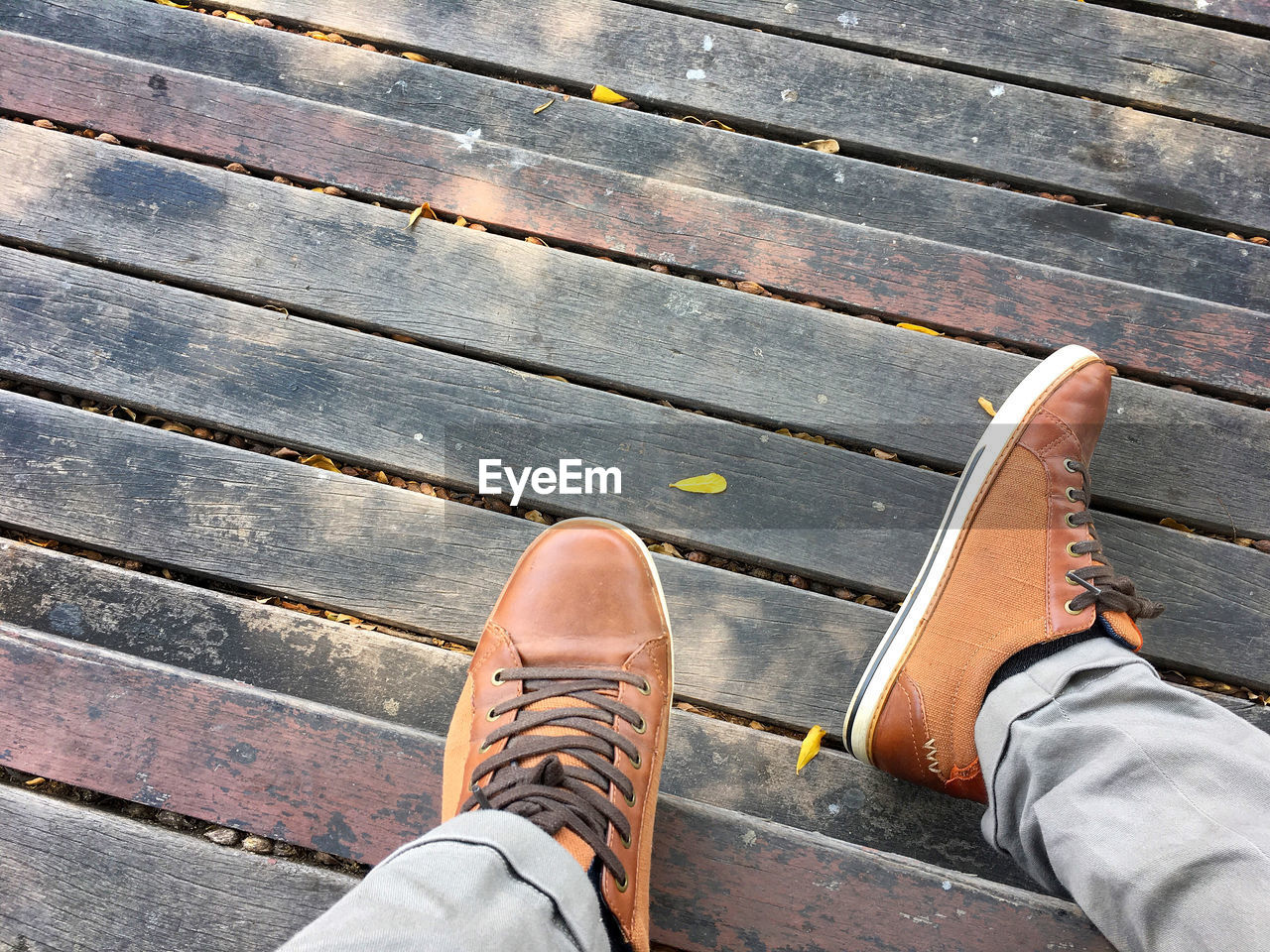 Low section of person wearing shoes on wooden floor