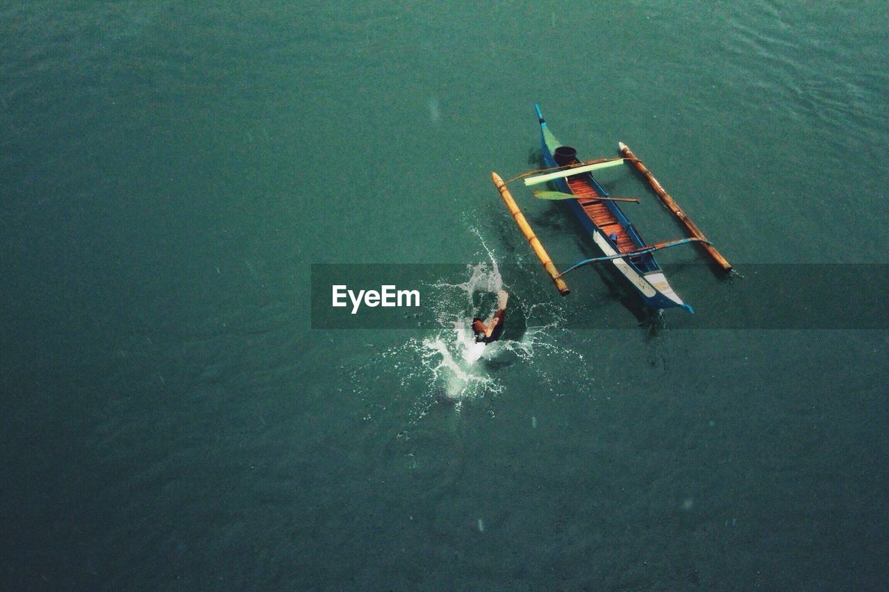 Aerial view of person diving into sea by outrigger canoe
