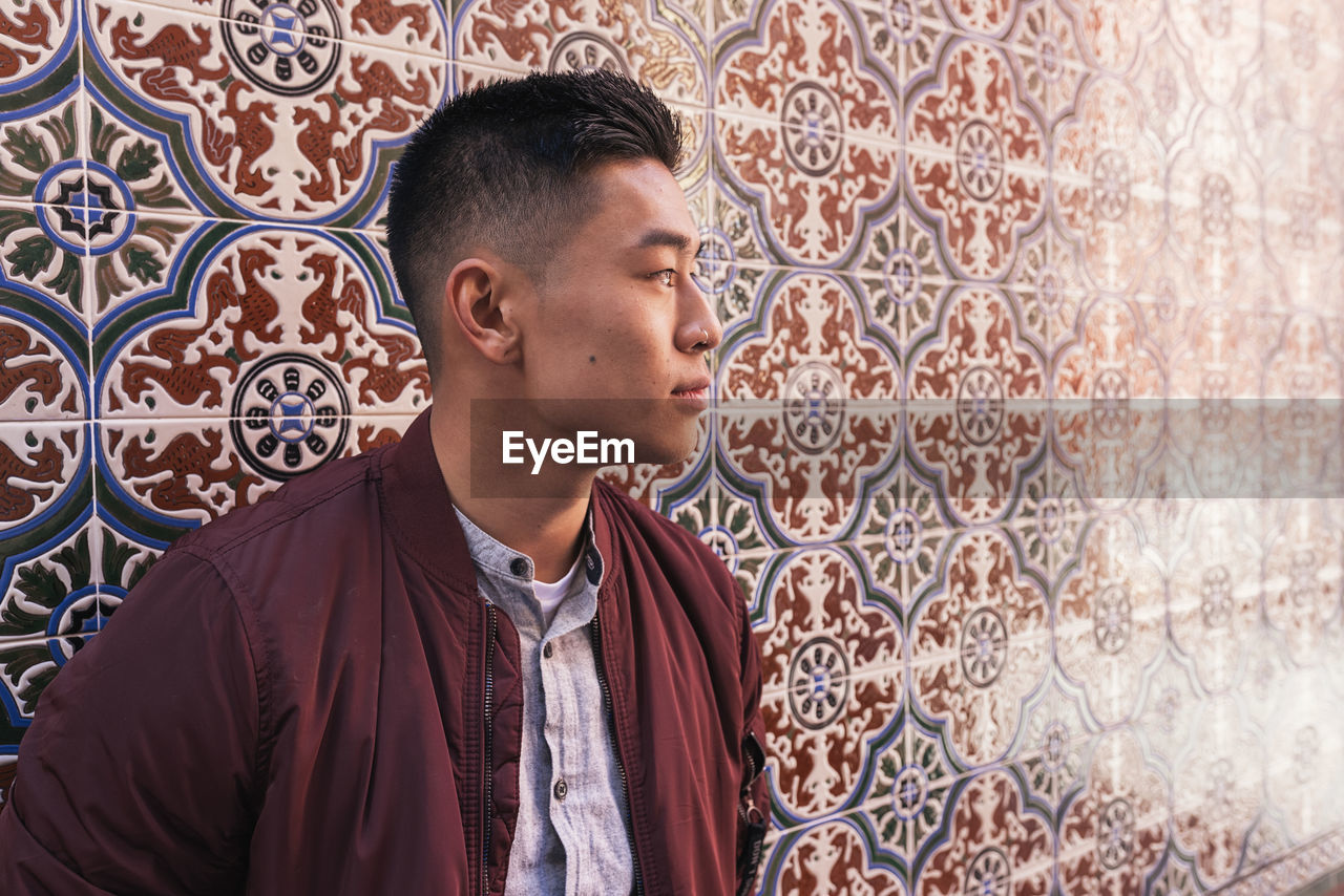 Young man looking away against wall