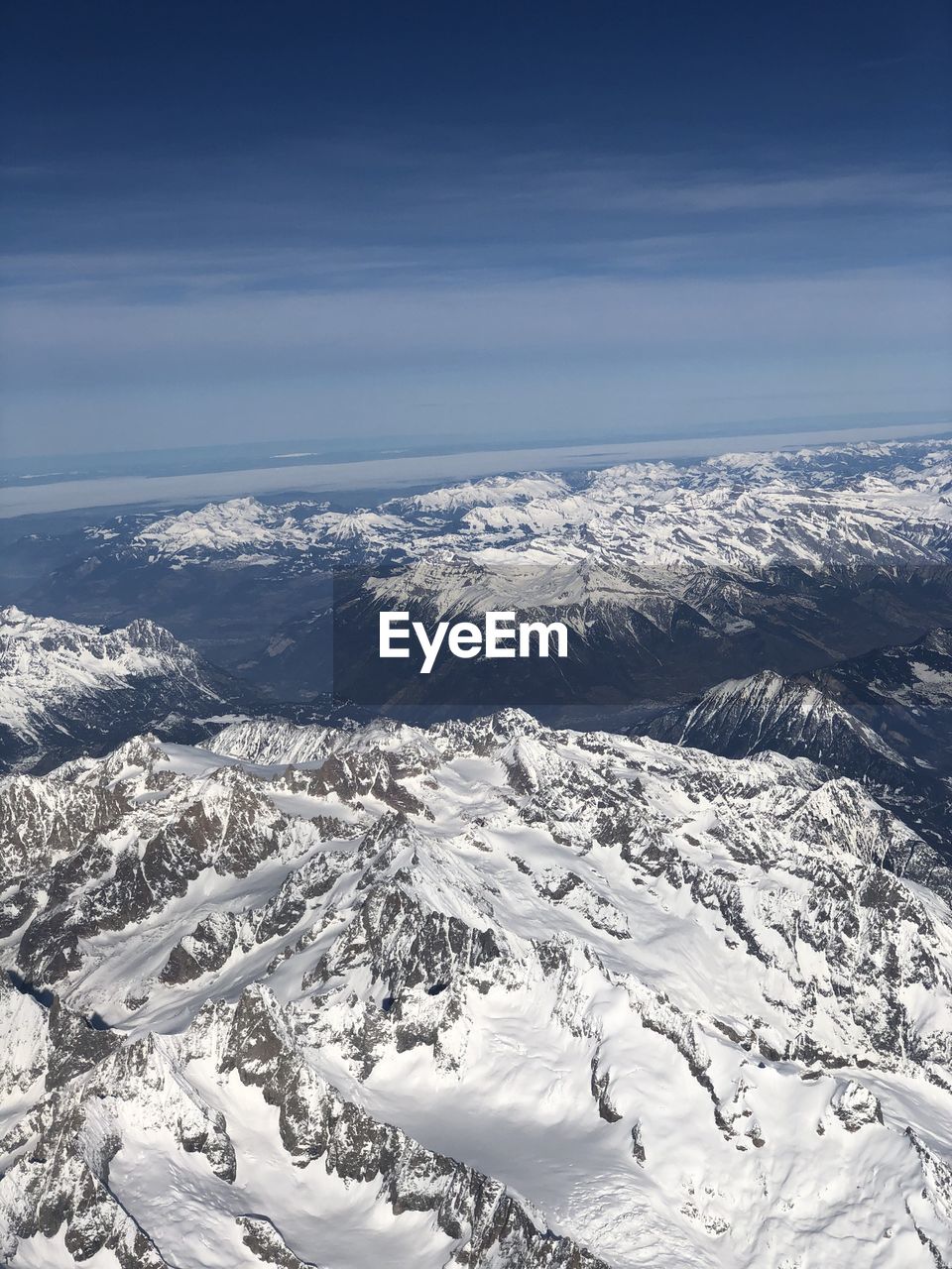 AERIAL VIEW OF SNOWCAPPED MOUNTAINS AGAINST SKY DURING WINTER