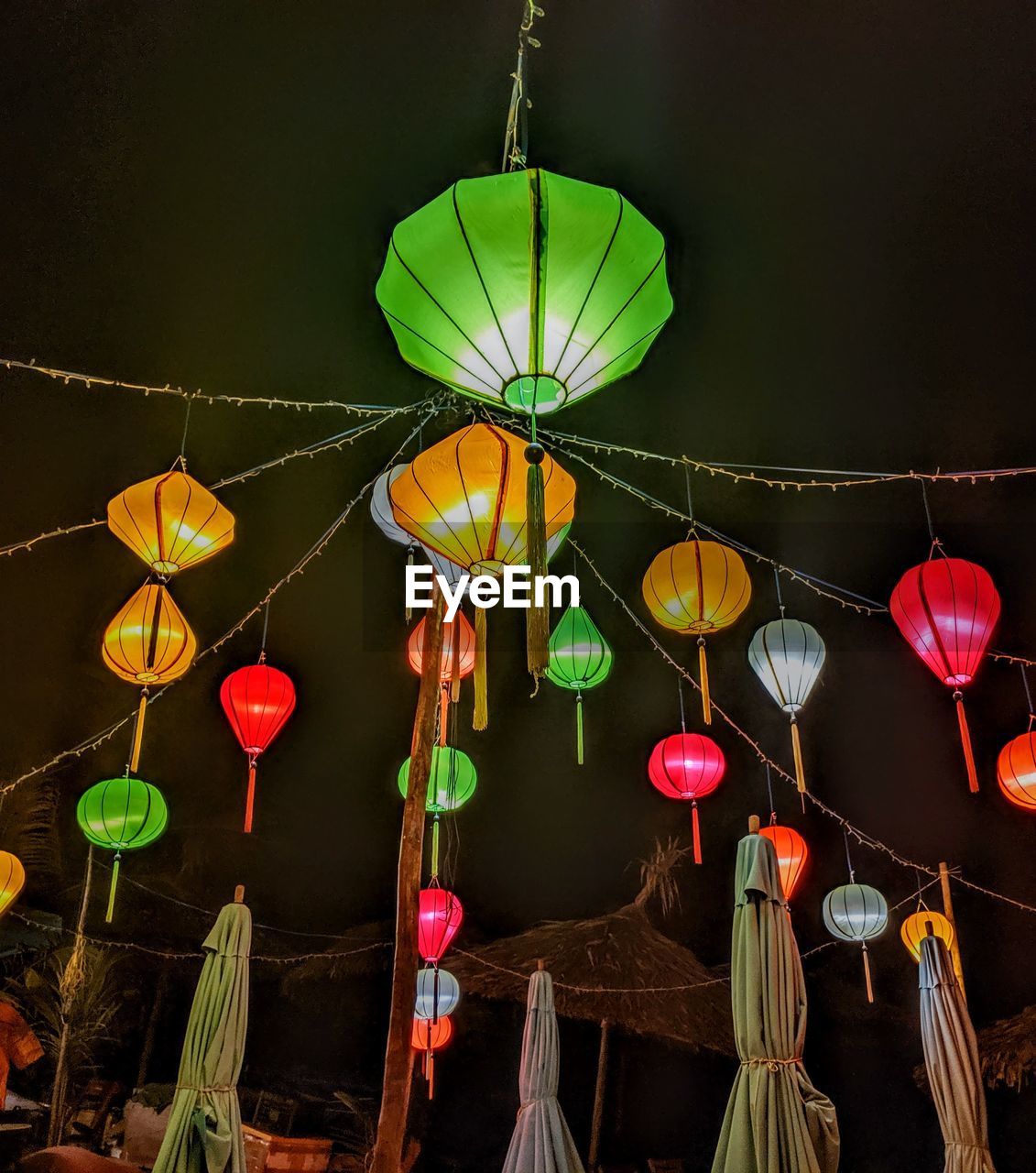 LOW ANGLE VIEW OF ILLUMINATED LANTERNS HANGING ON NIGHT