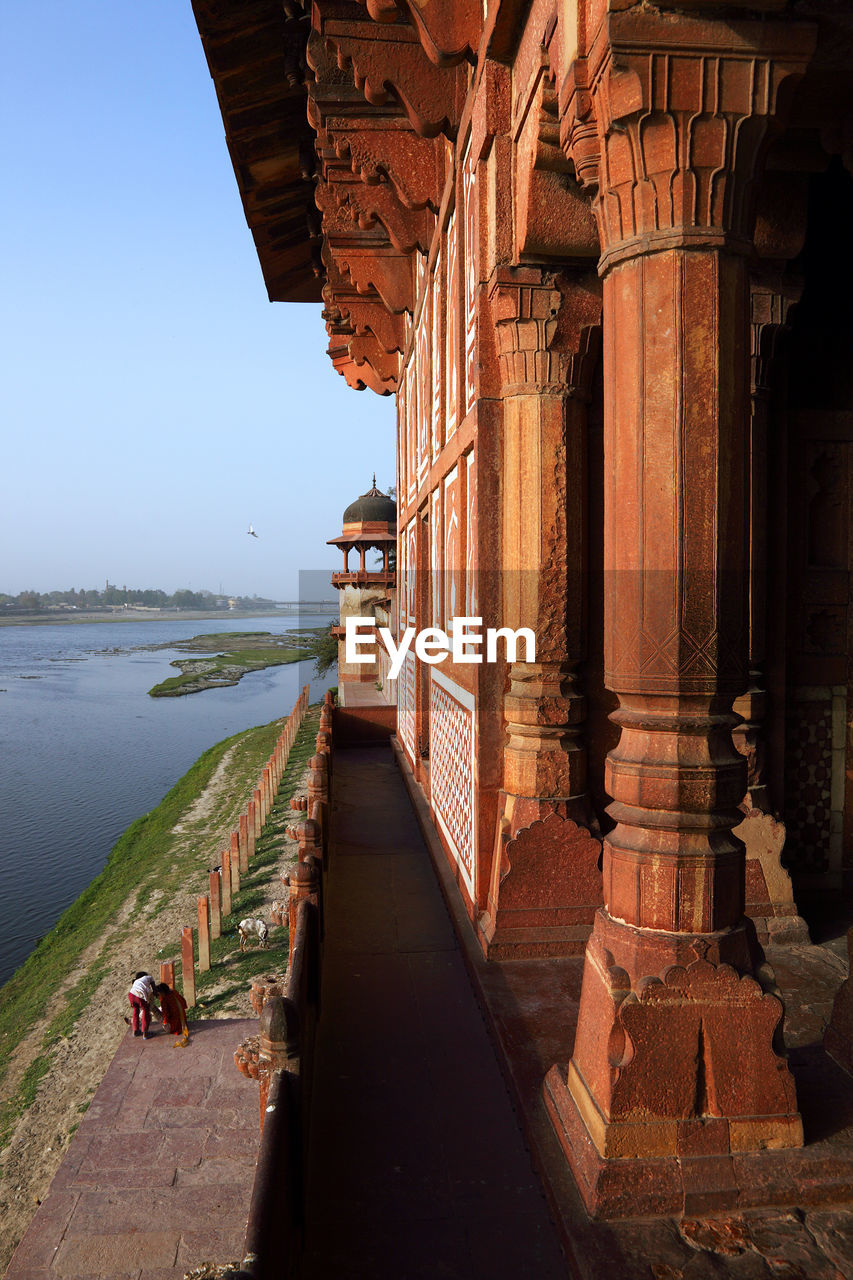 Agra fort by lake against clear sky