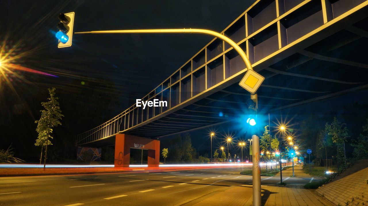 LIGHT TRAILS ON BRIDGE OVER STREET AT NIGHT