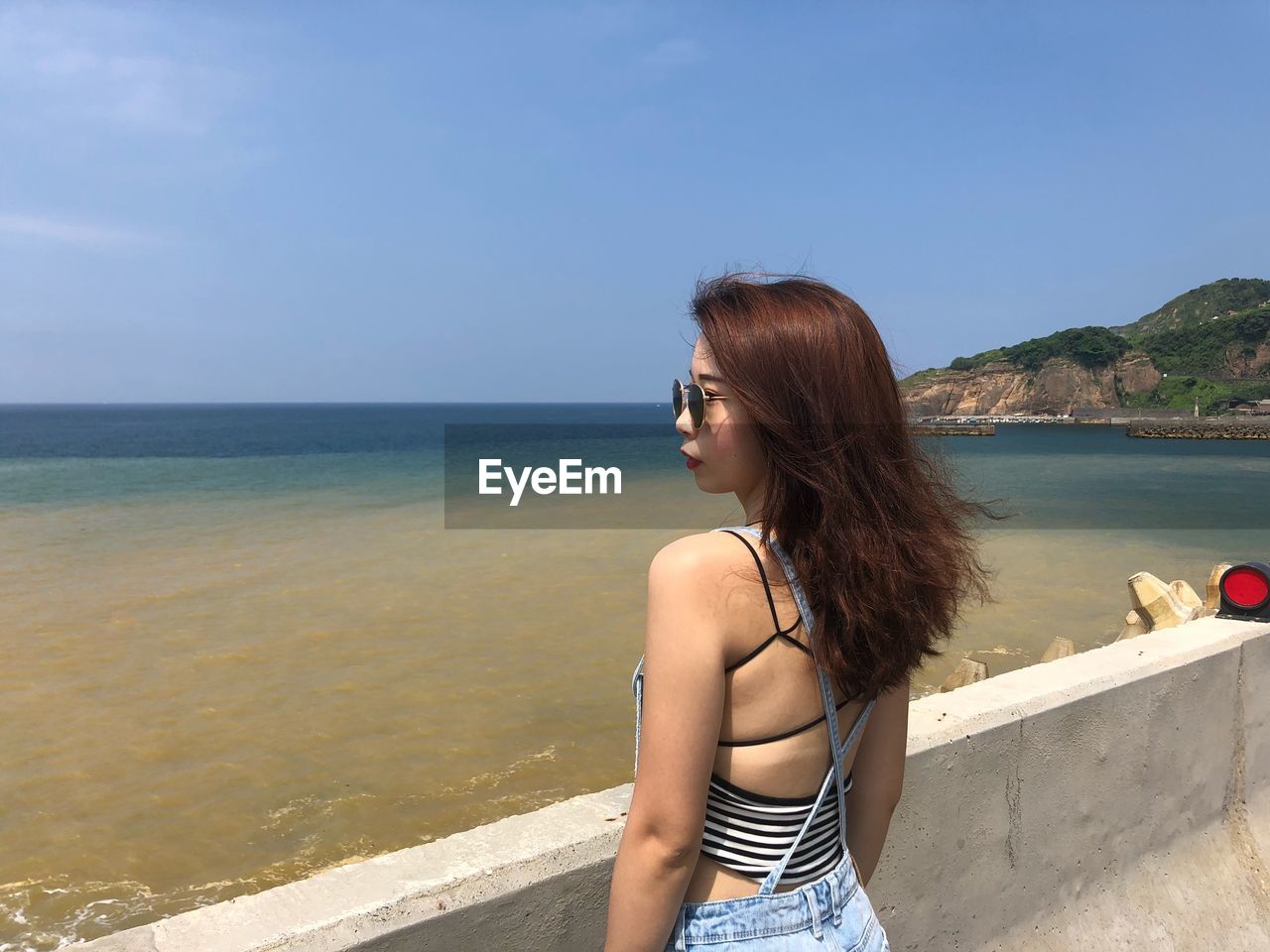 YOUNG WOMAN ON BEACH AGAINST SKY