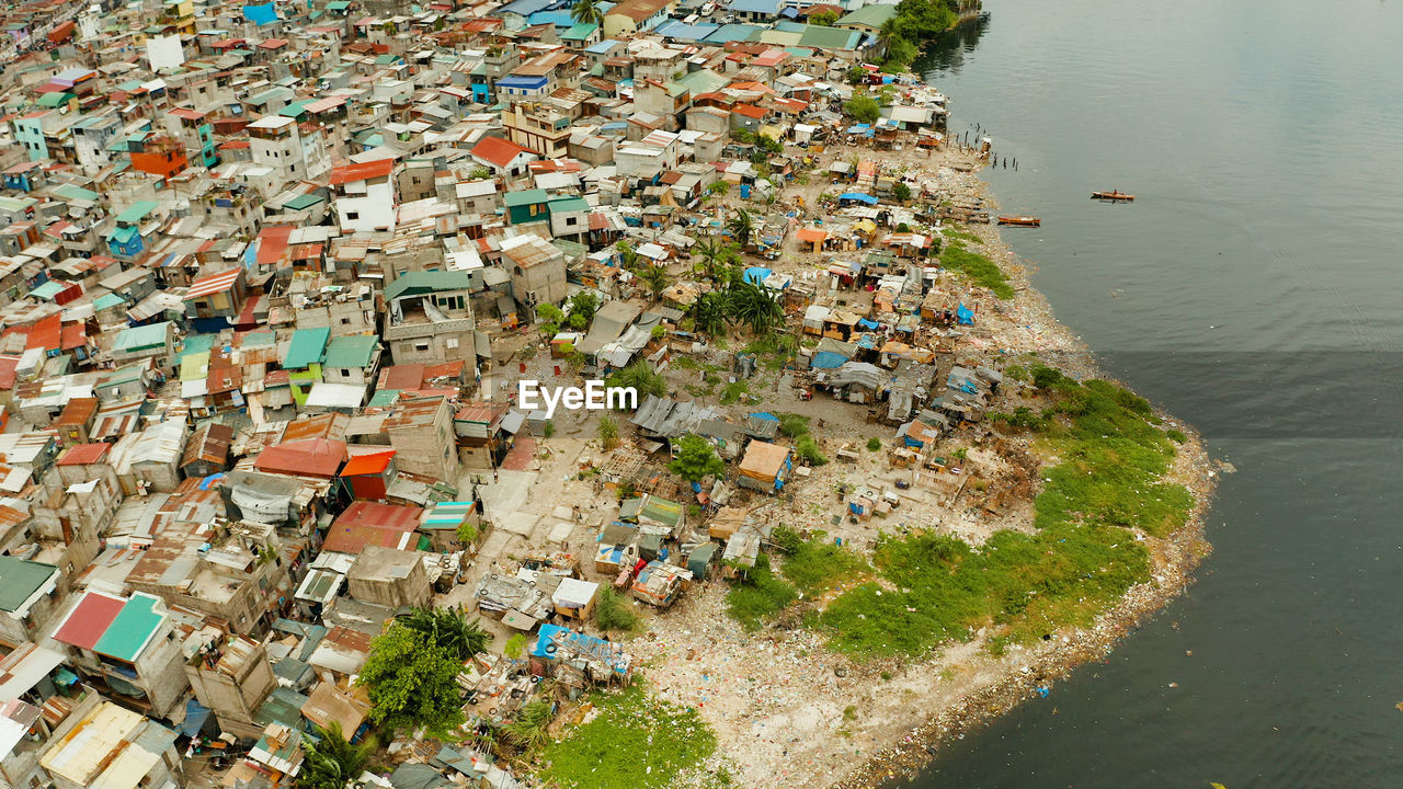 Slums in manila on the bank of a river polluted with garbage, aerial view.