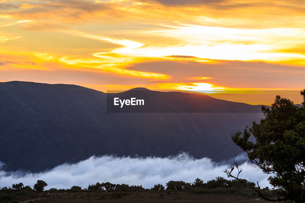 Scenic view of mountains against orange sky