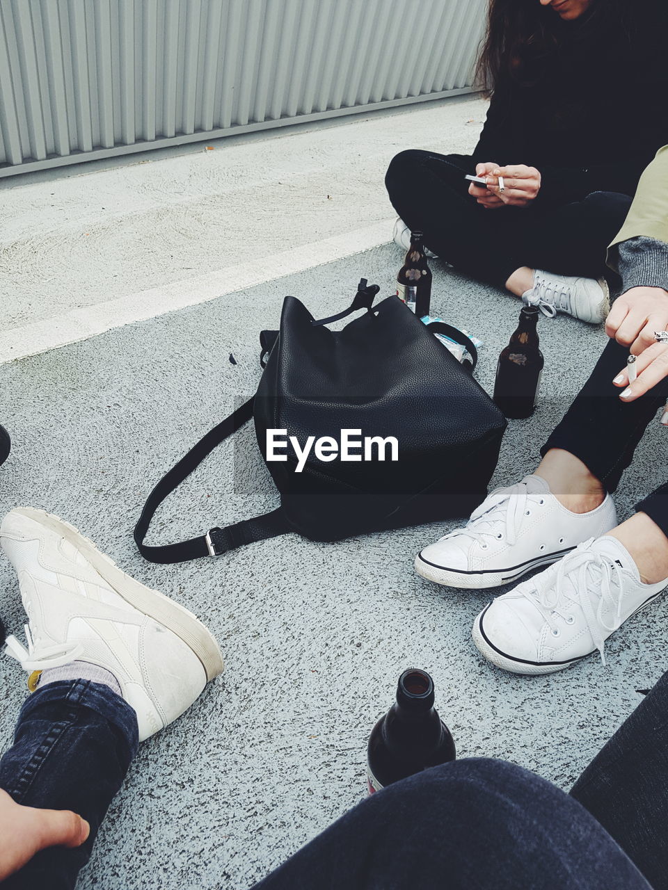 Low section of people with bottles sitting on rooftop