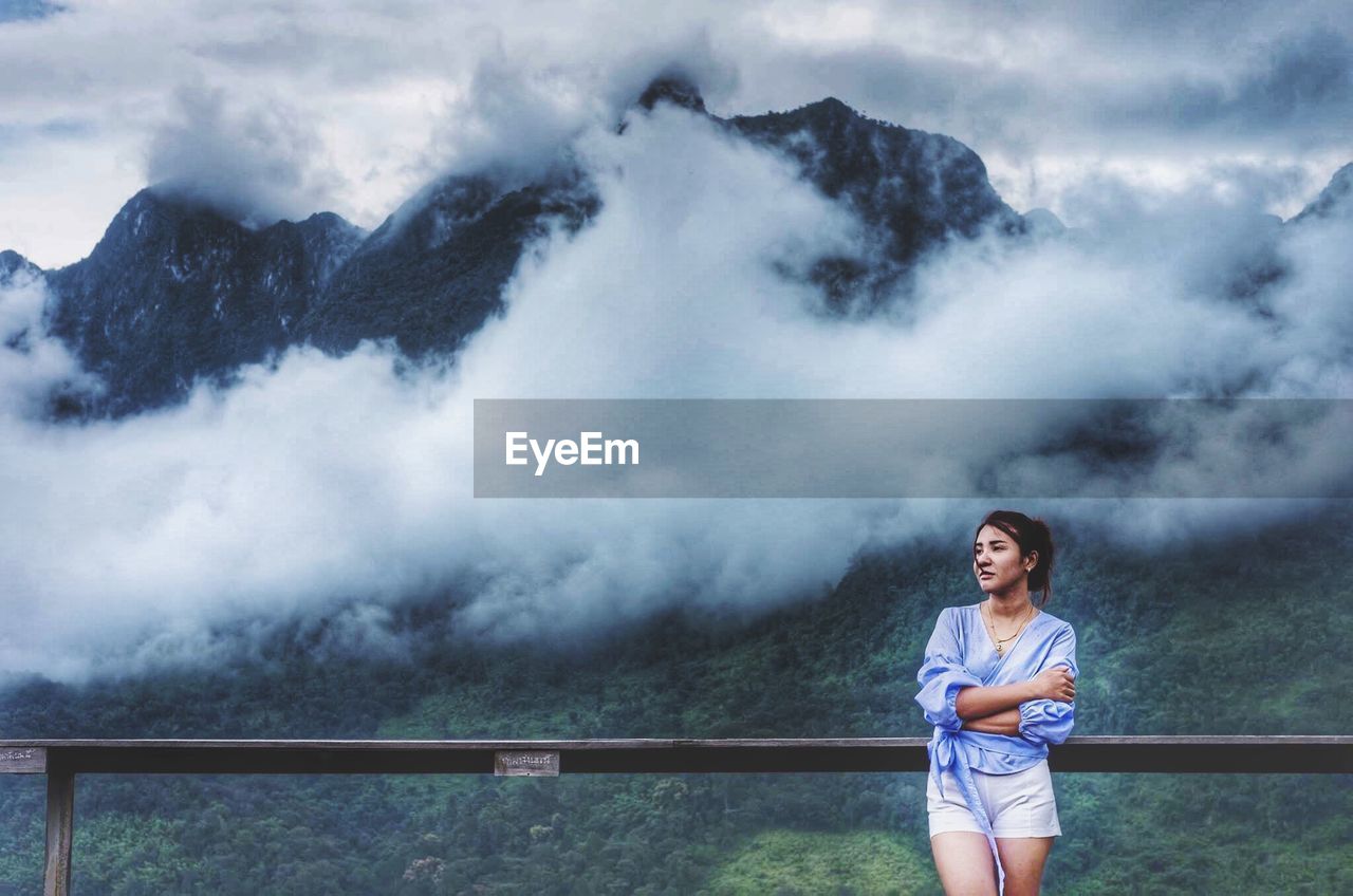 Woman standing by railing against mountains