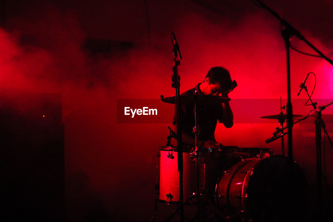 Drummer sitting by drums during music concert