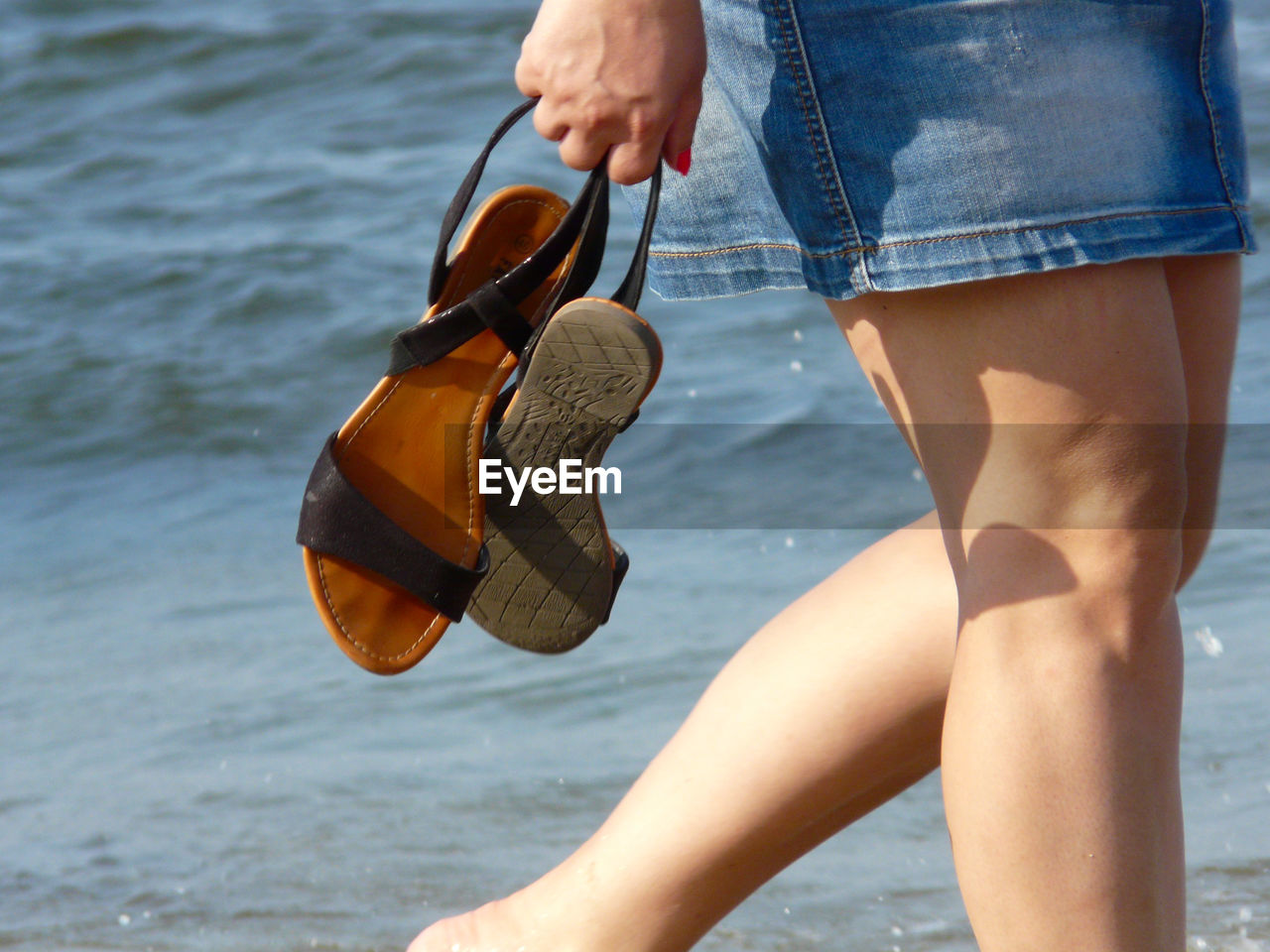 LOW SECTION OF MAN HOLDING SEA BY WATER