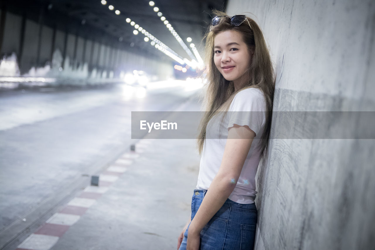 Portrait of woman standing in illuminated tunnel