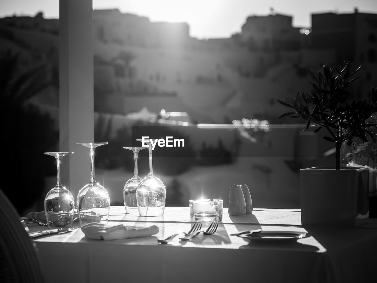 Restaurant table decorated with glasses on terrace in sunset light on the island santorini, greece