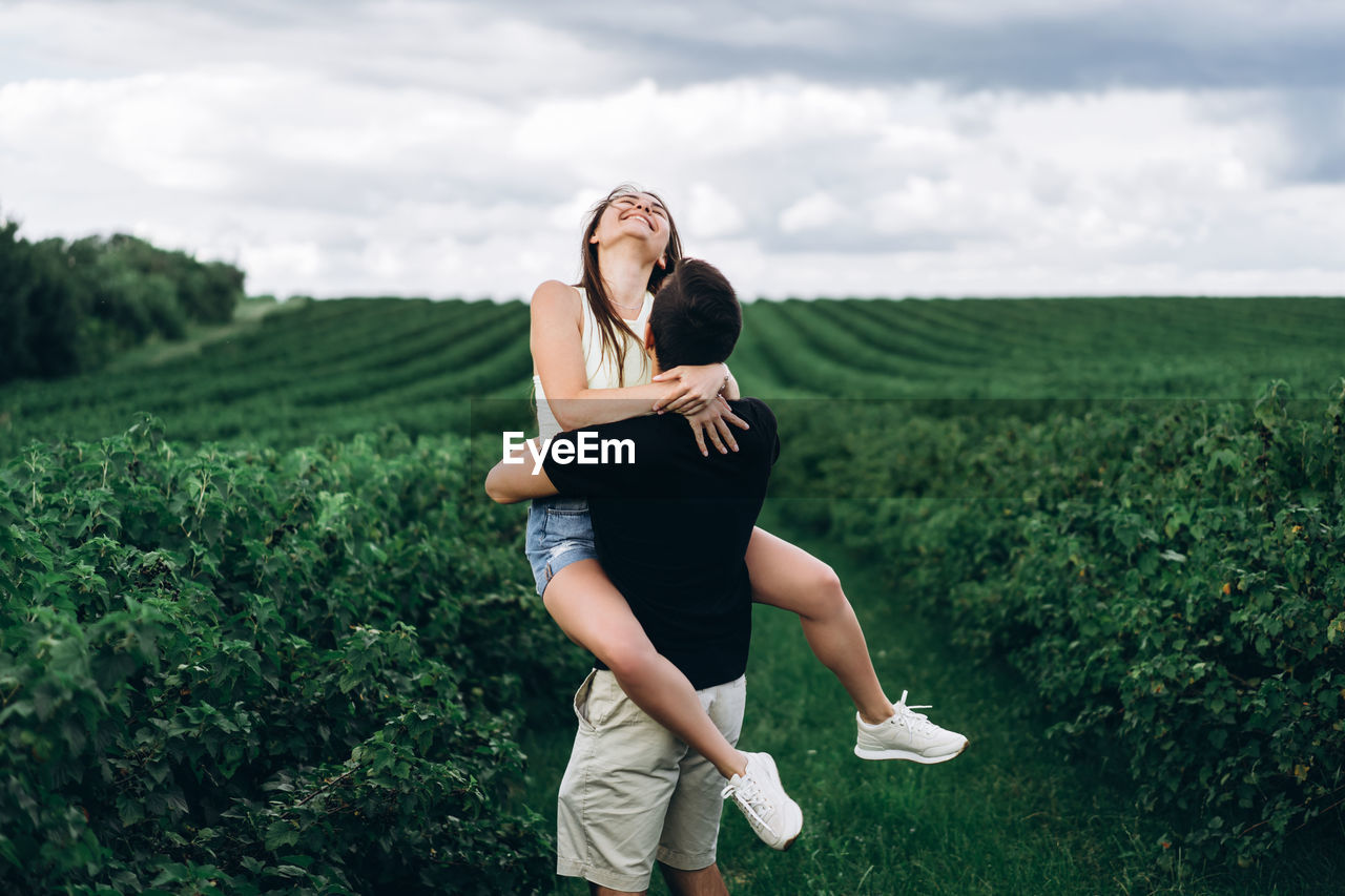 Full length of woman and man standing on field against sky