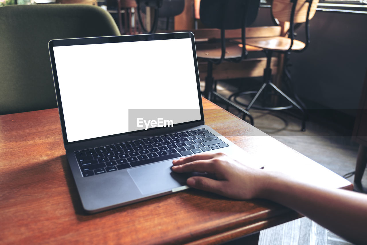 Cropped hand of person using laptop on table