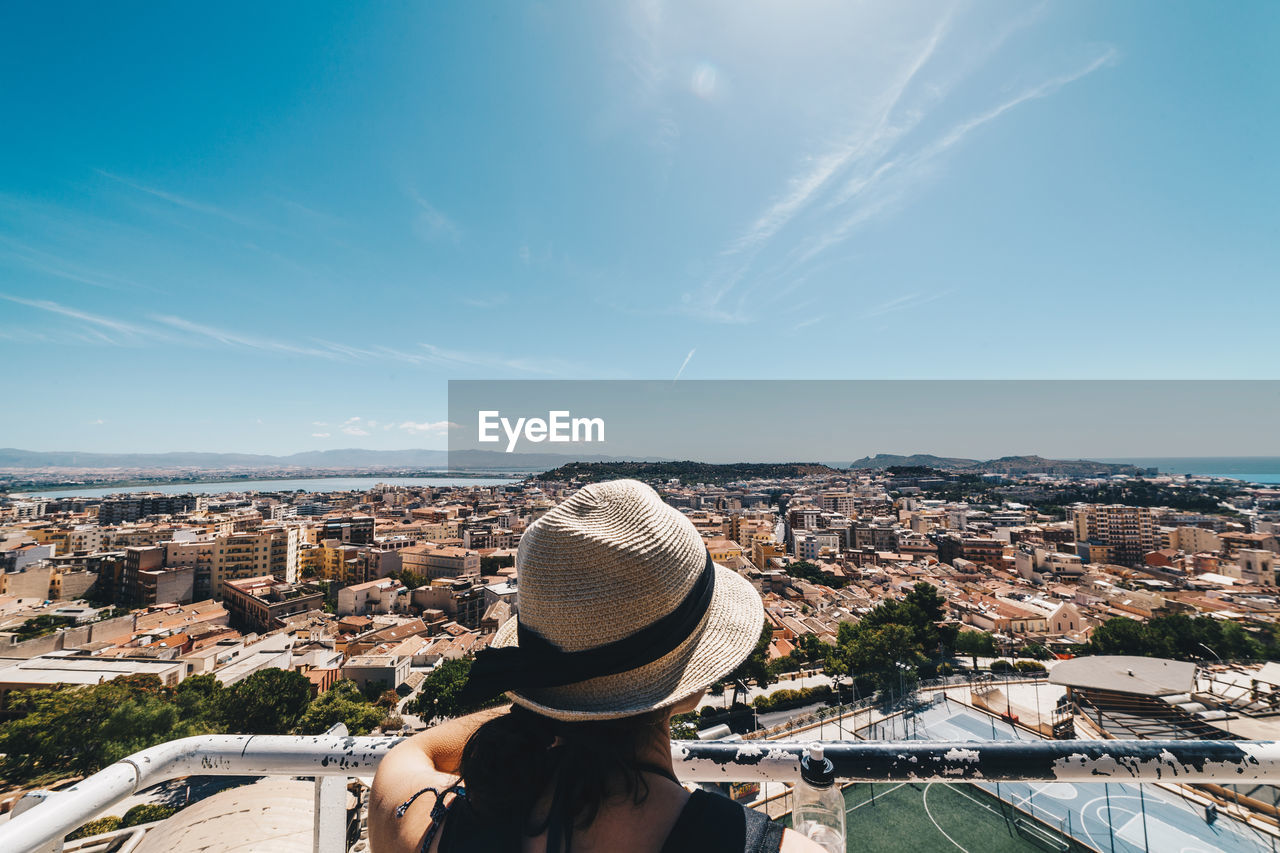 Rear view of woman looking at cityscape against sky