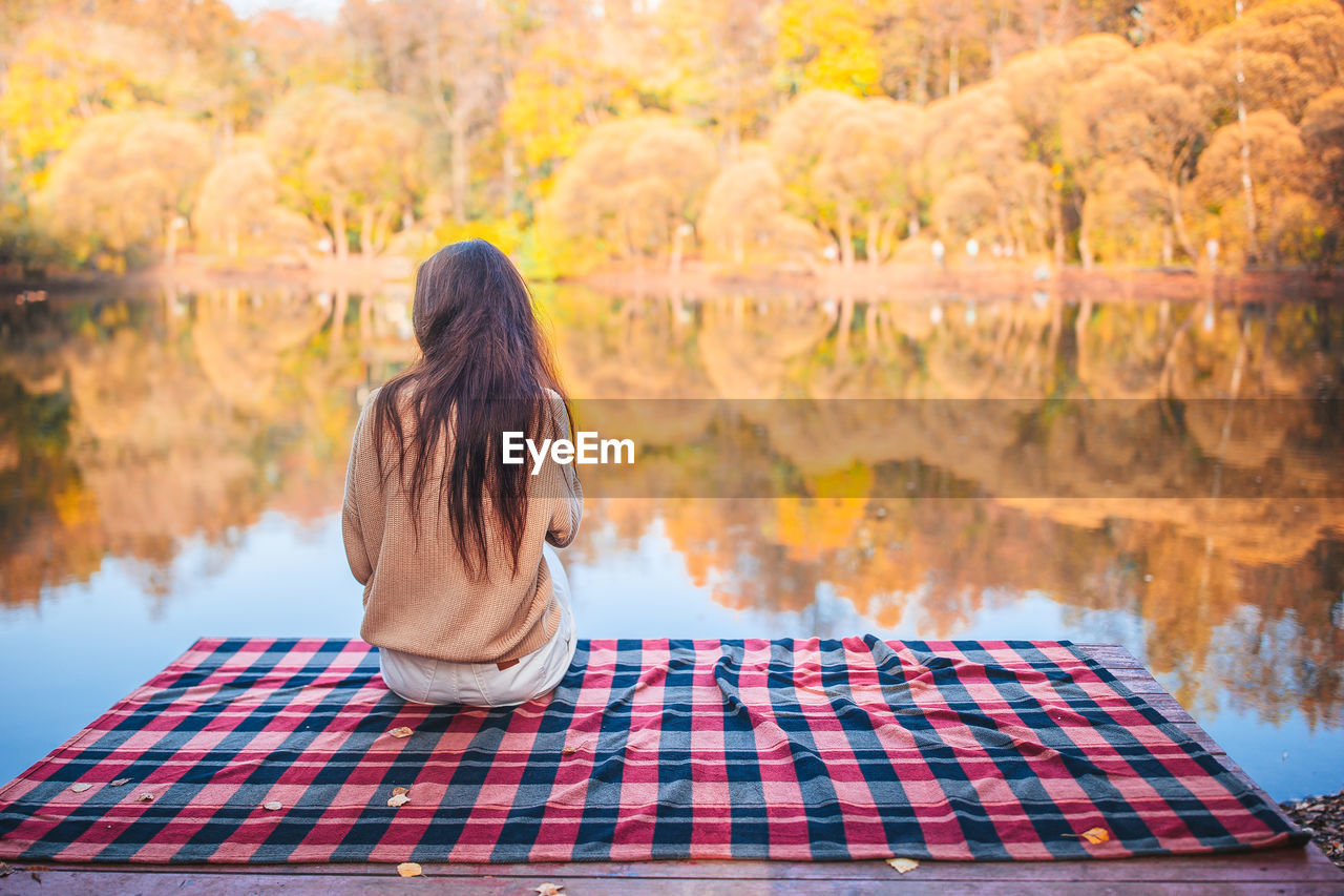 REAR VIEW OF WOMAN STANDING BY TREES DURING AUTUMN