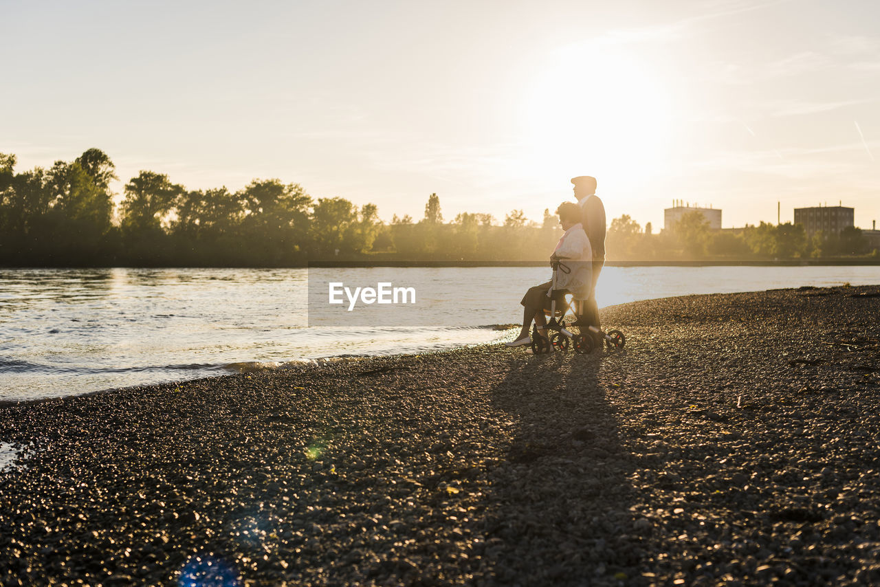 Senior couple with wheeled walker on the beach at sunset