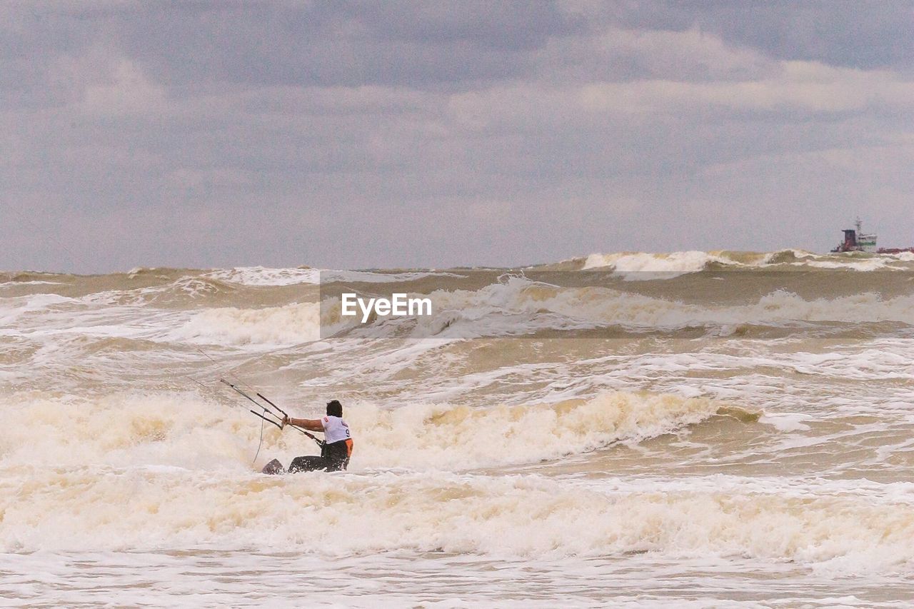 Man kiteboarding on sea against sky