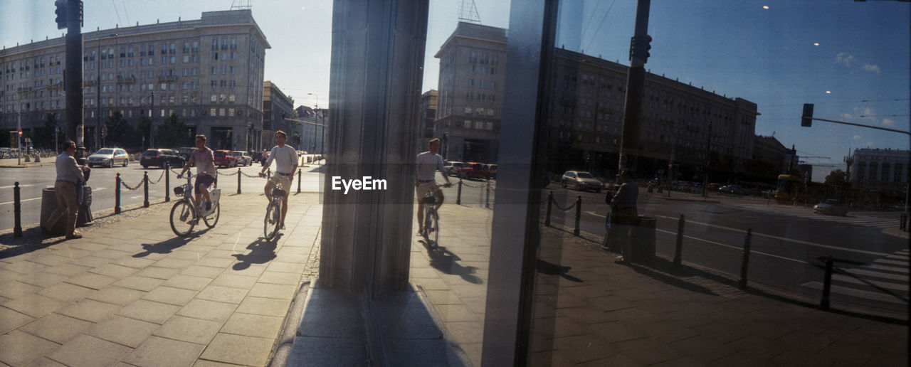 PEOPLE WALKING ON SIDEWALK BY STREET IN CITY