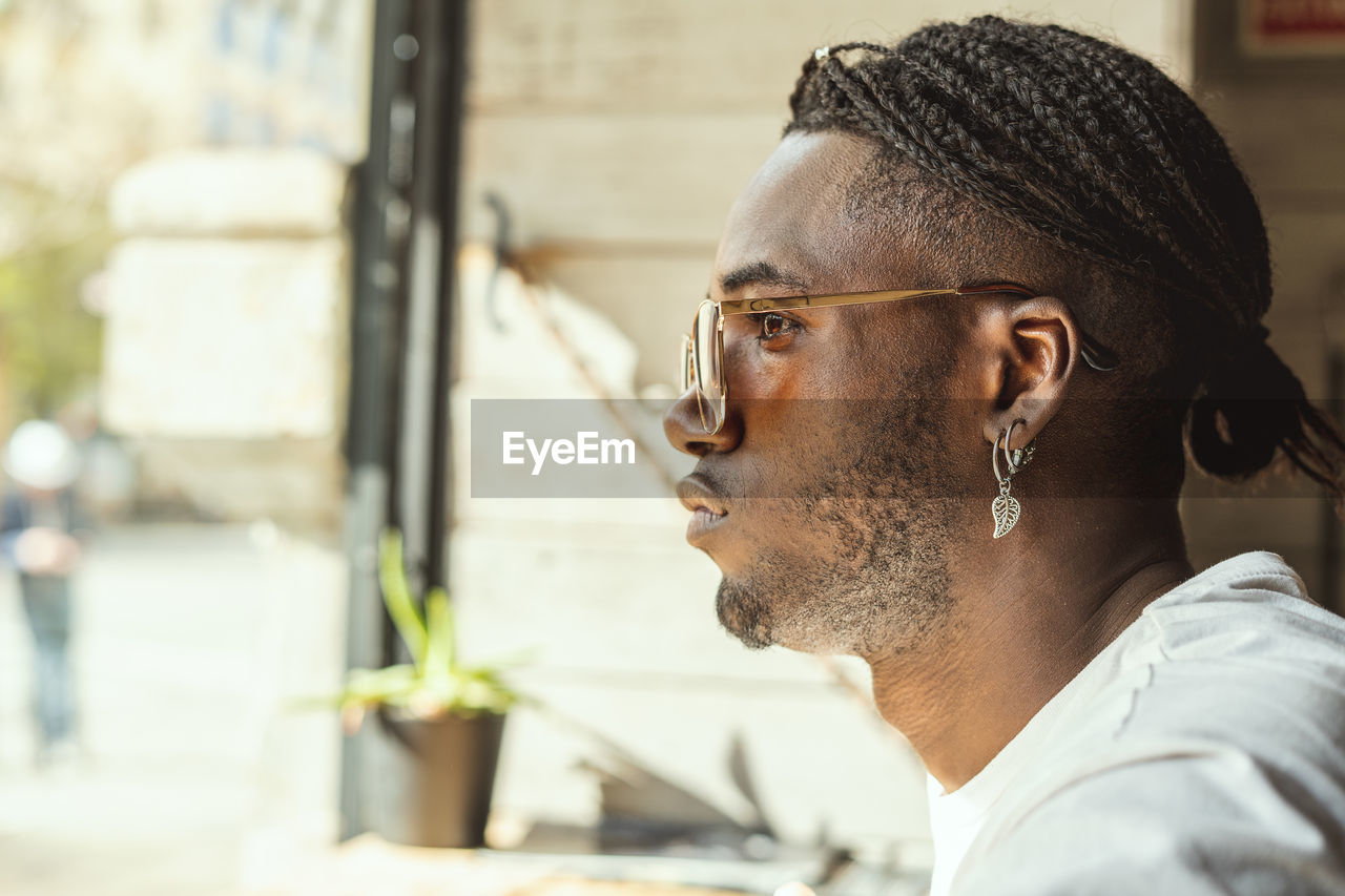 Close-up of young man looking away while sitting at cafe 