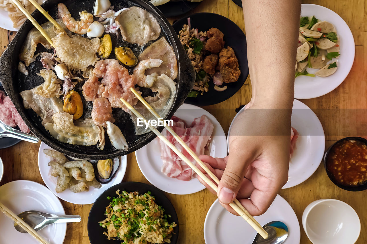 Bbq barbecue eating. people grilling  pork, meal, shellfish and shrimp with wooden chopsticks.