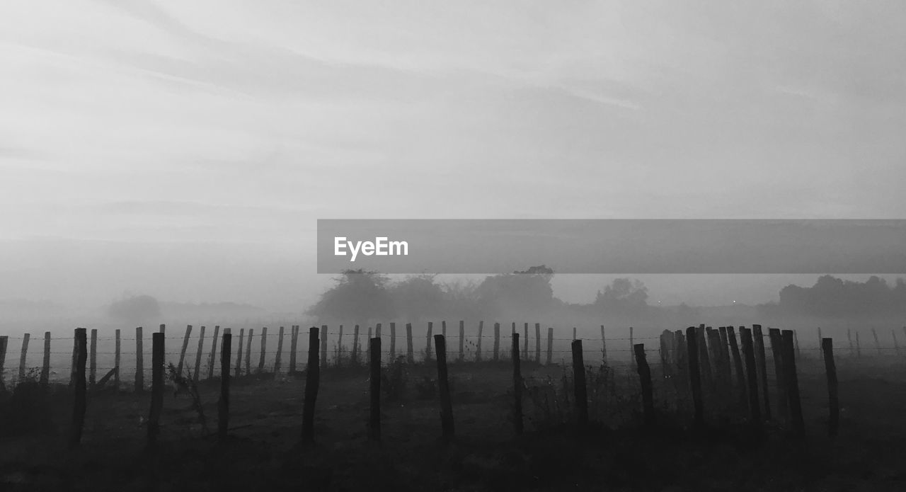 Wooden fence on landscape against sky