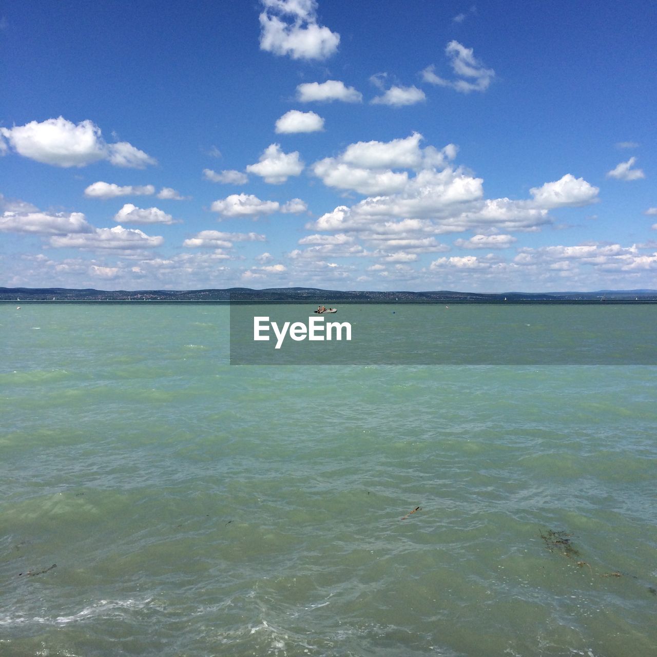 Distant view of people in lake balaton against sky