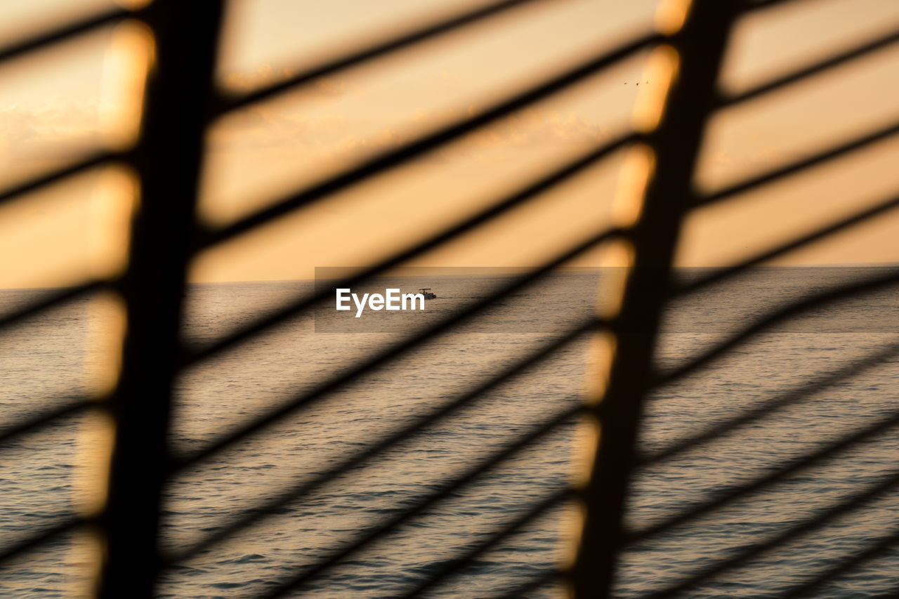 Sea seen through blinds during sunset