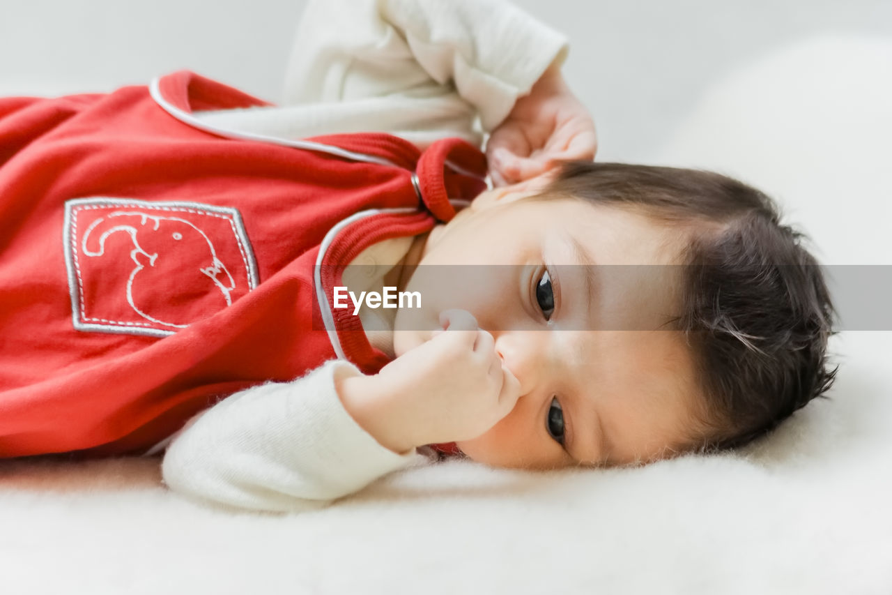 Portrait of cute baby girl lying on bed