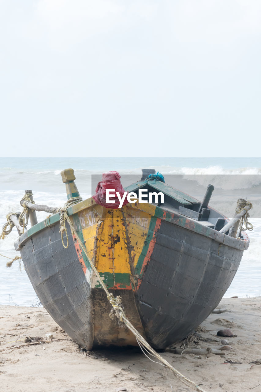 Boat moored on beach against clear sky