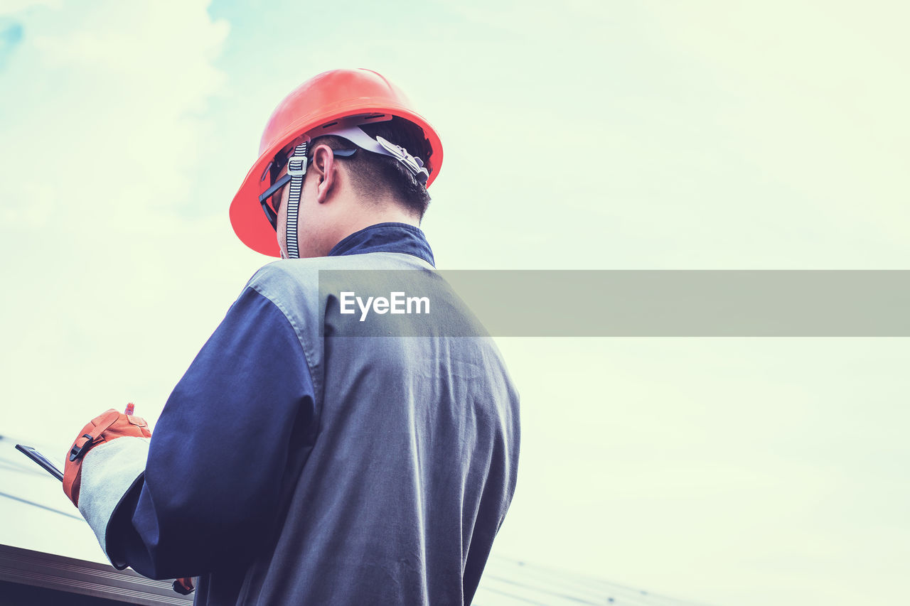 Engineer writing in file while standing at factory