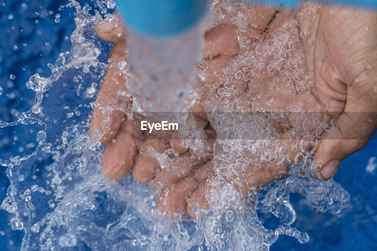 Close-up of hand holding water under pipe