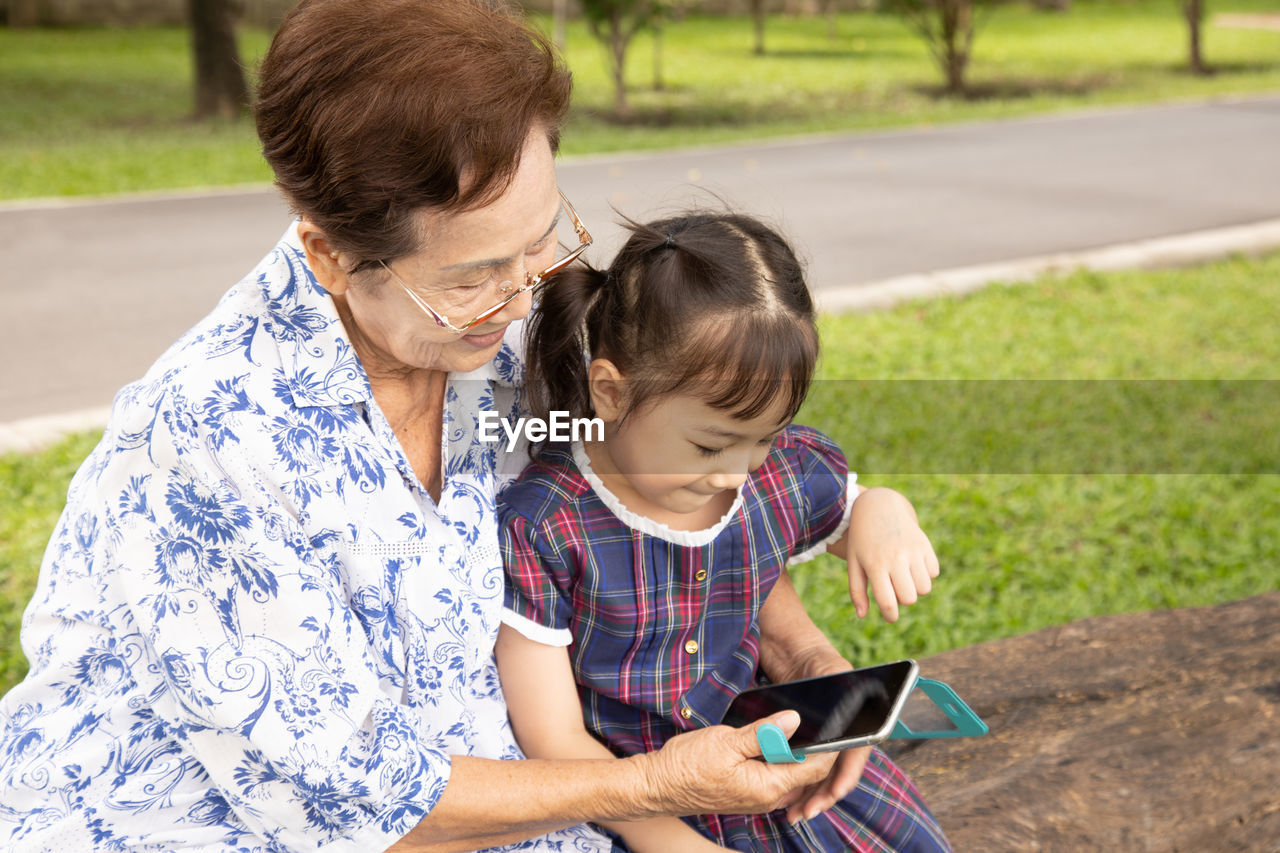 Senior woman and girl using mobile phone