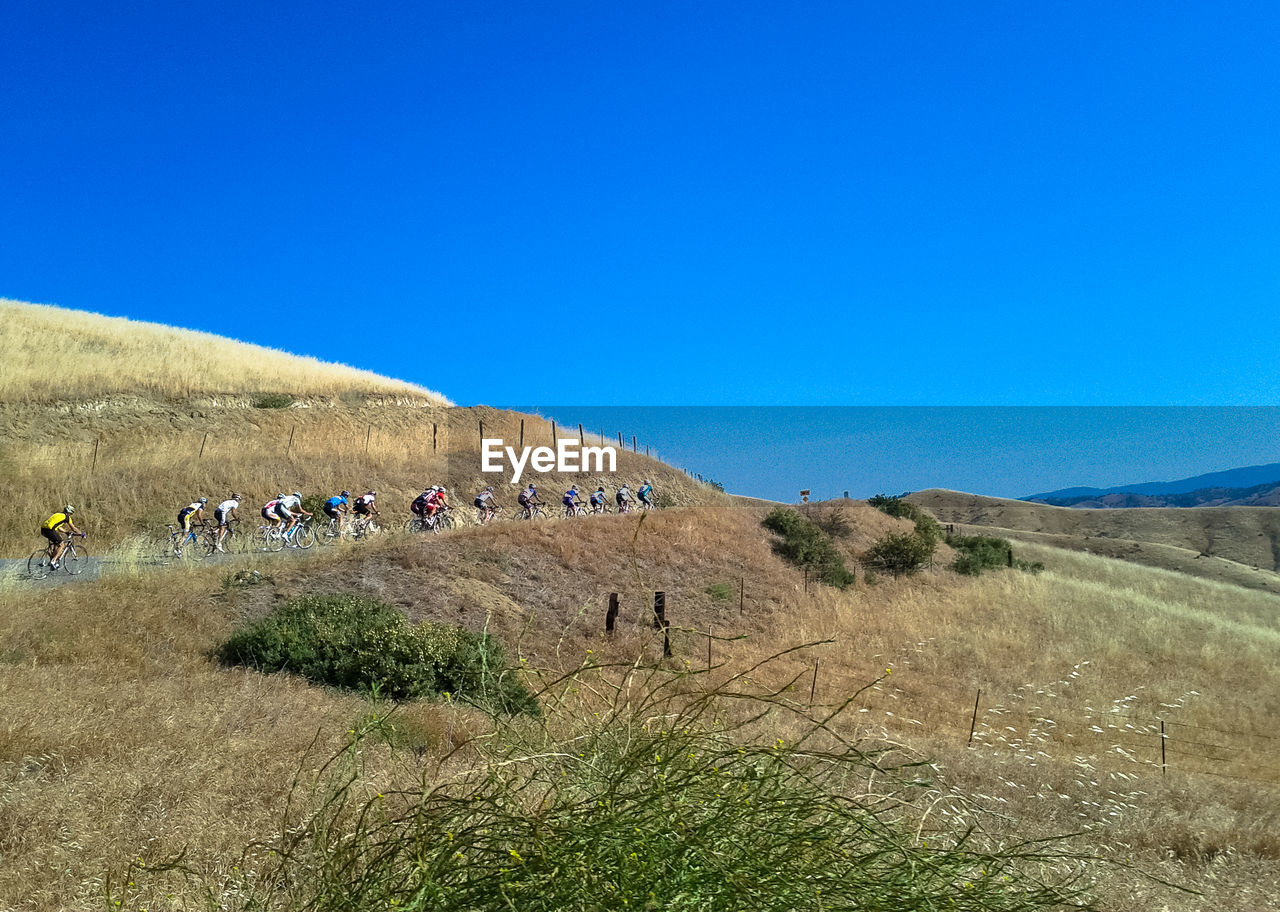 People riding bicycle on mountain road against clear blue sky