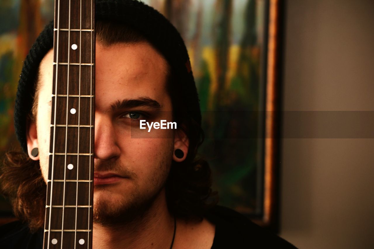 Close-up portrait of handsome man in front of guitar at home