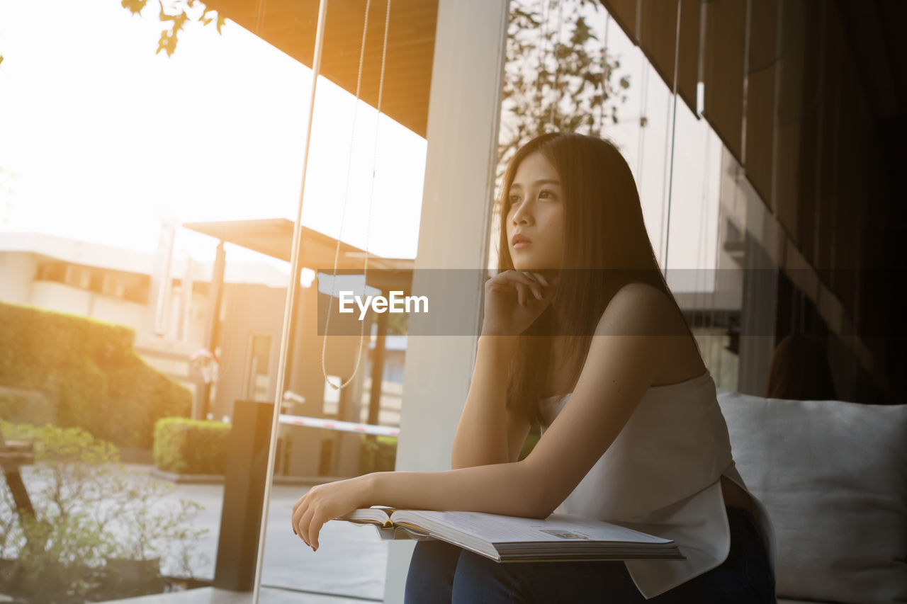 Thoughtful young woman looking through window