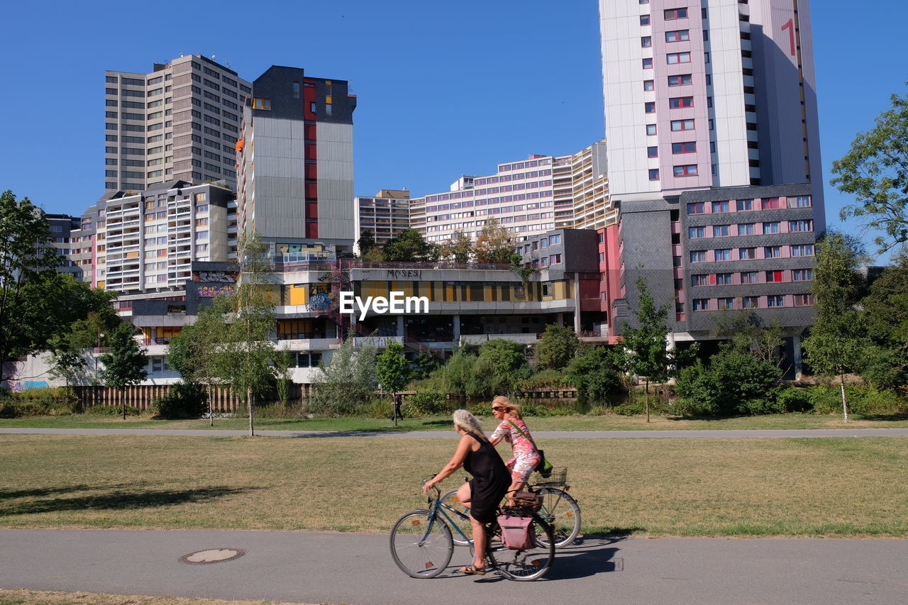 MAN RIDING BICYCLE ON STREET AGAINST BUILDINGS