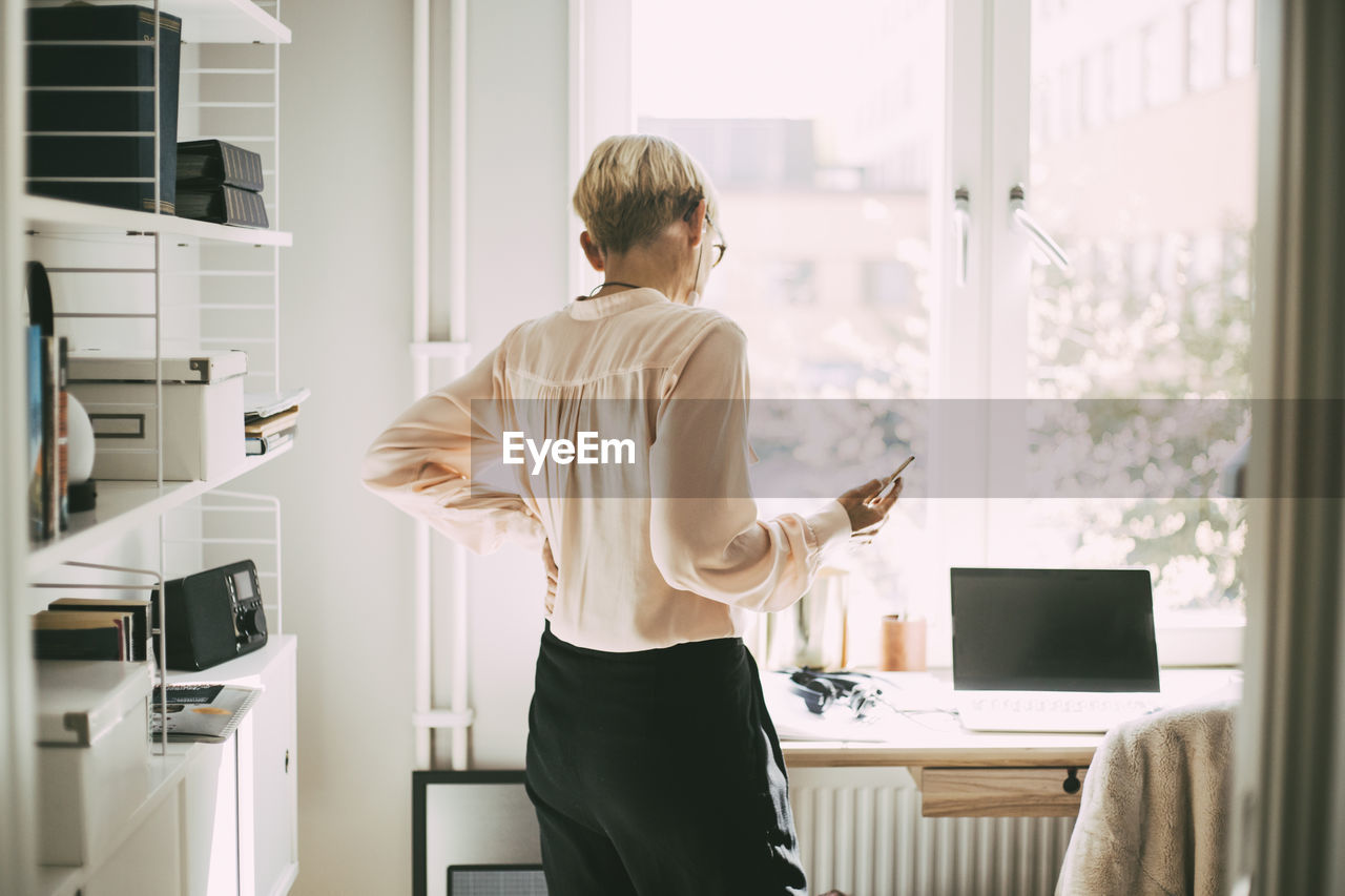 Rear view of woman in office at home talking on the phone