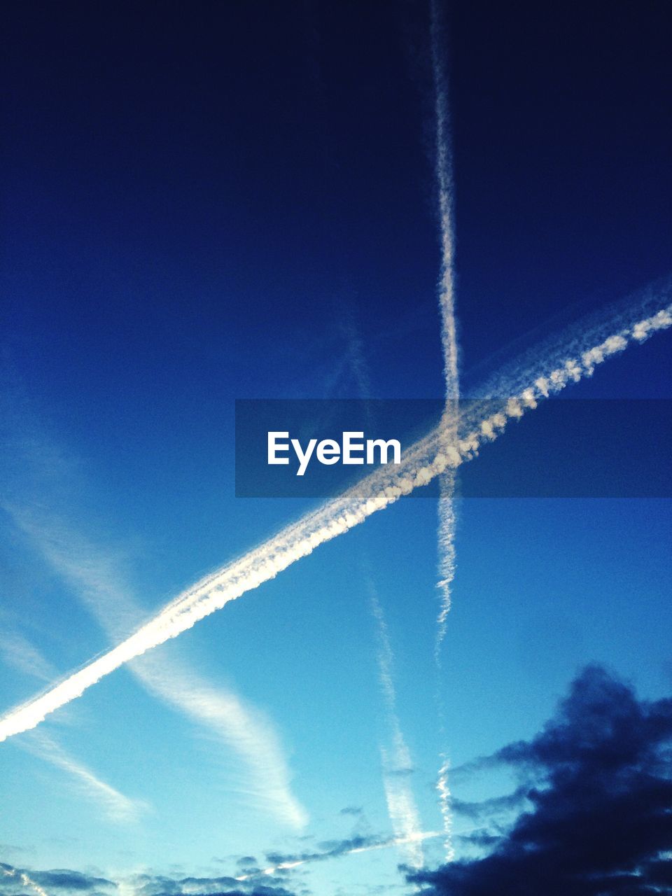 LOW ANGLE VIEW OF VAPOR TRAILS IN BLUE SKY