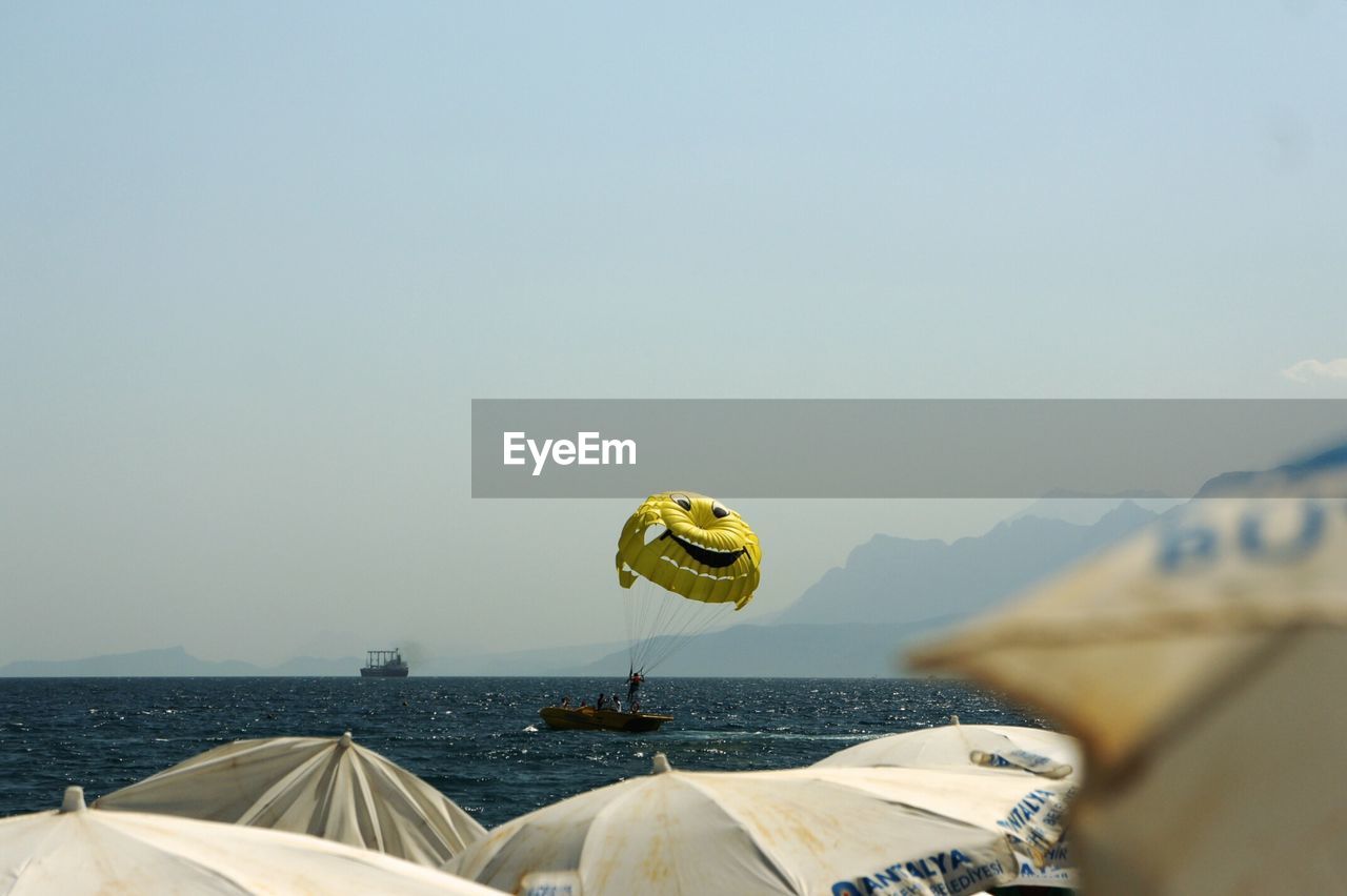 Smiley face parachute over sea against sky