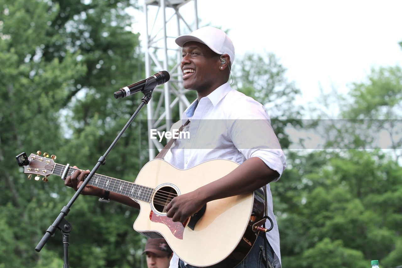 FULL LENGTH OF MAN PLAYING GUITAR AT CAMERA