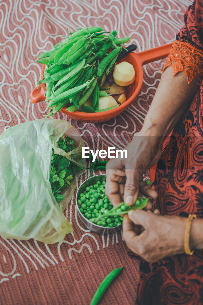 HIGH ANGLE VIEW OF WOMAN HOLDING VEGETABLES ON TABLE