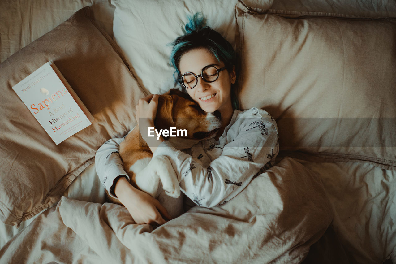 HIGH ANGLE VIEW OF DOG LYING DOWN ON BED