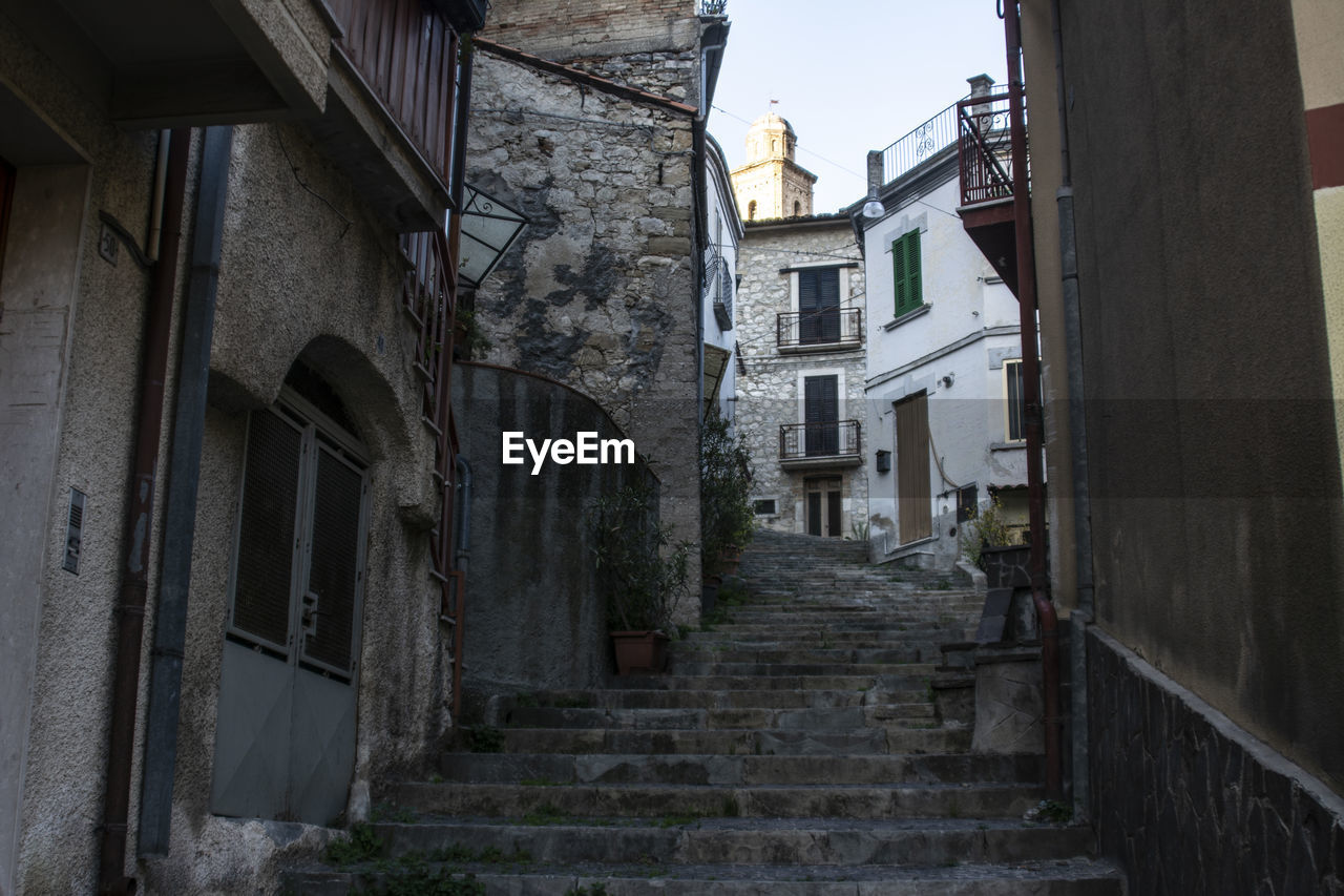 LOW ANGLE VIEW OF STAIRCASE AMIDST BUILDINGS