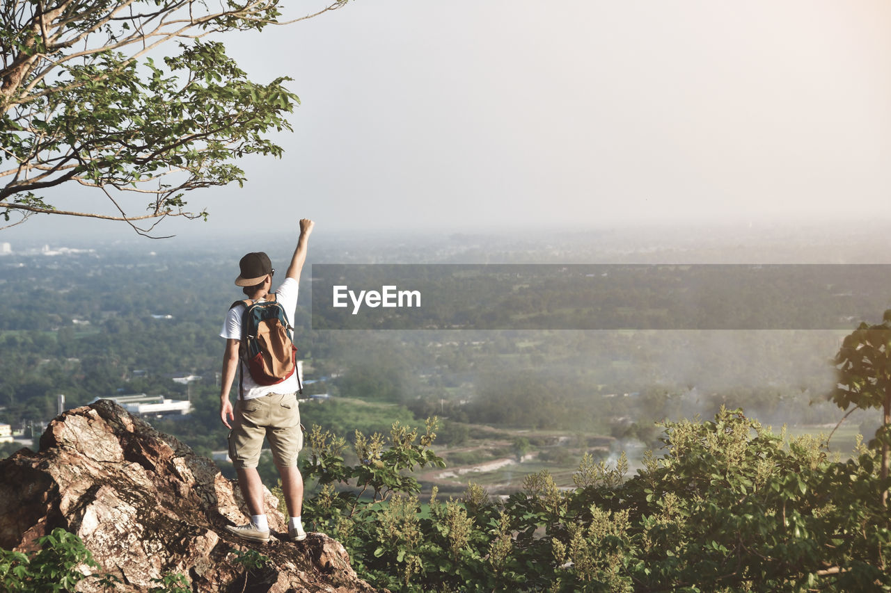 Rear view full length of man standing against landscape on rock