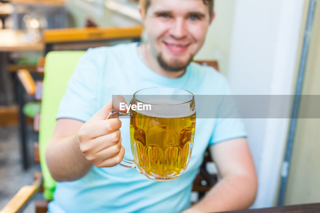 PORTRAIT OF YOUNG MAN DRINKING GLASSES