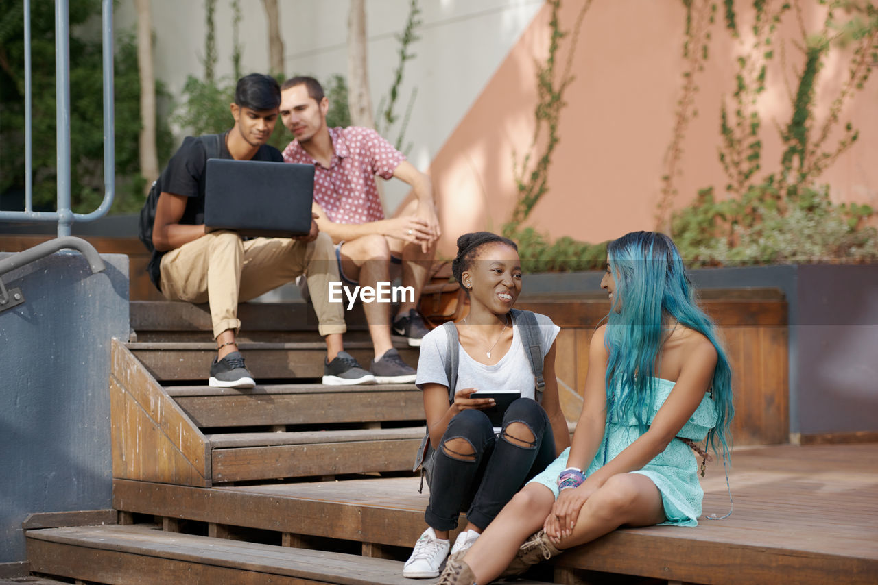 Smiling friends sitting on steps