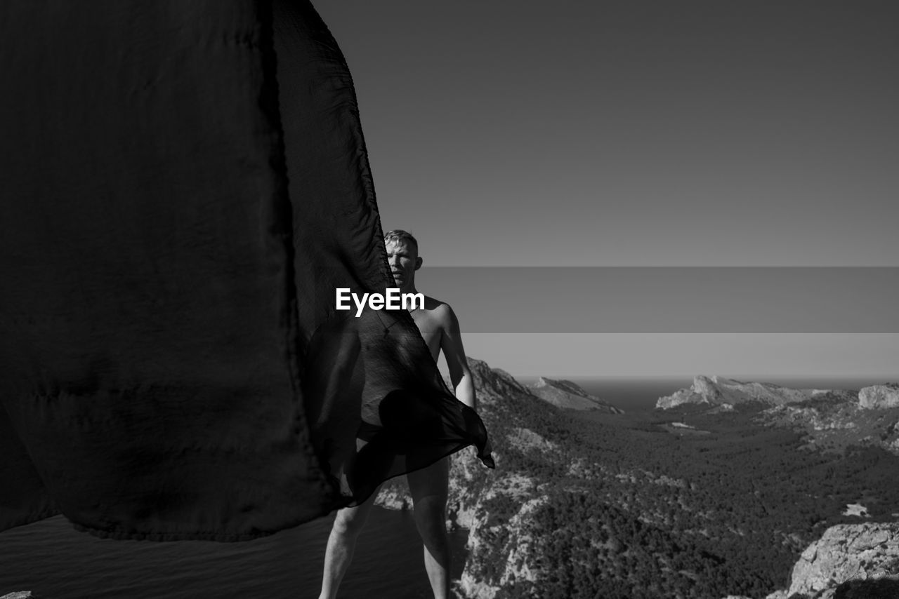 Shirtless man in front of mountains