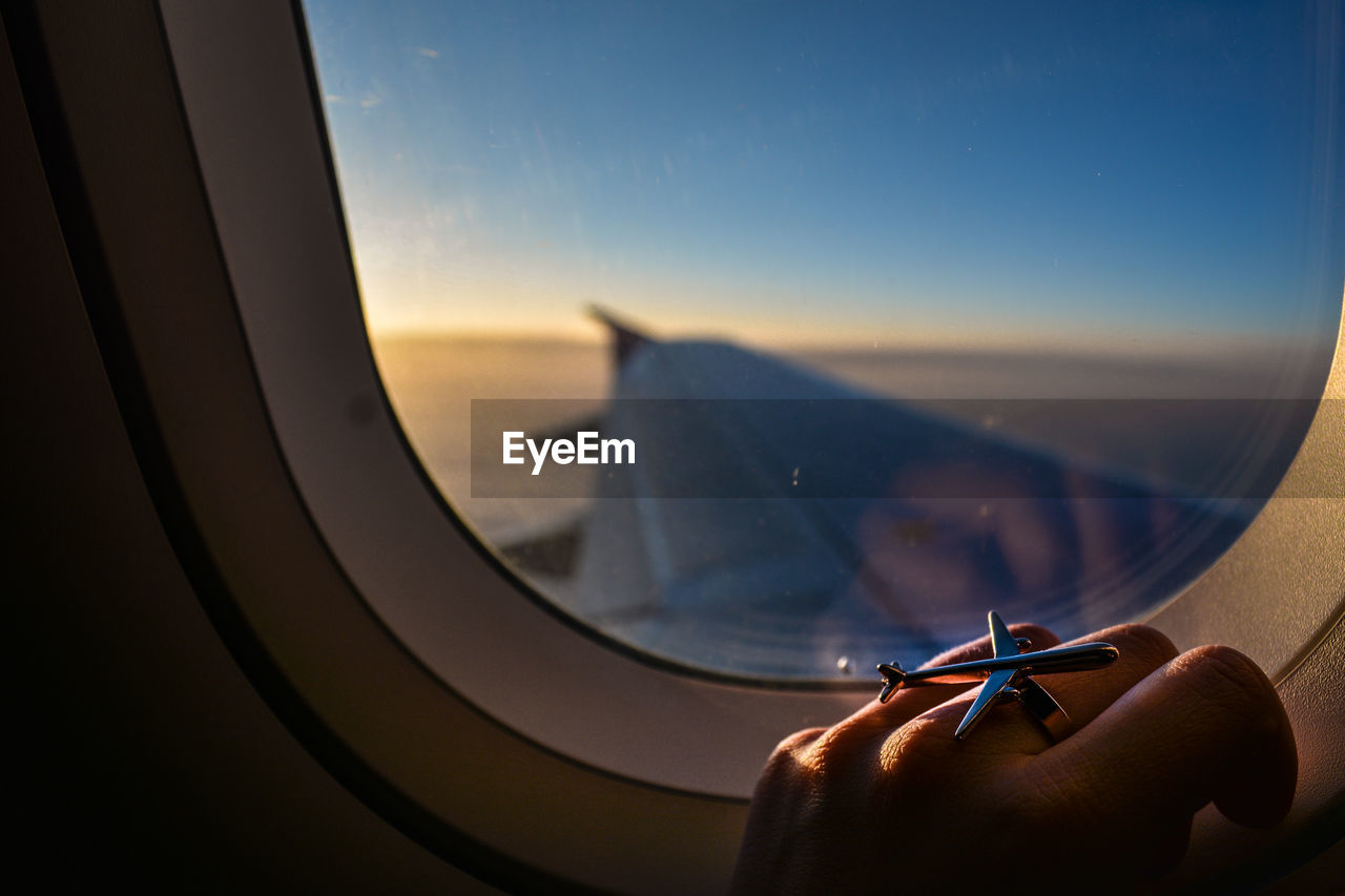 Cropped image of hand on window in airplane