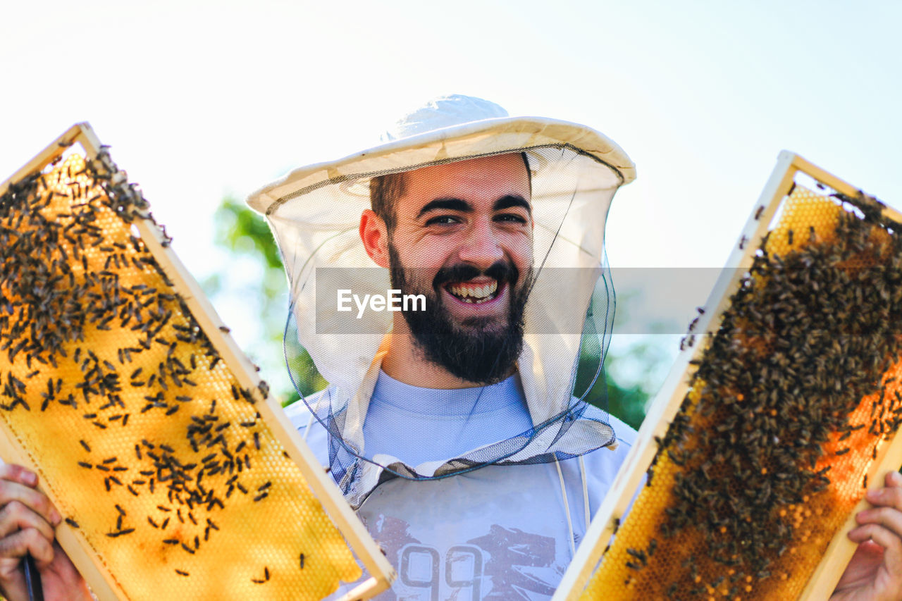 Close-up of man holding bee hive at farm